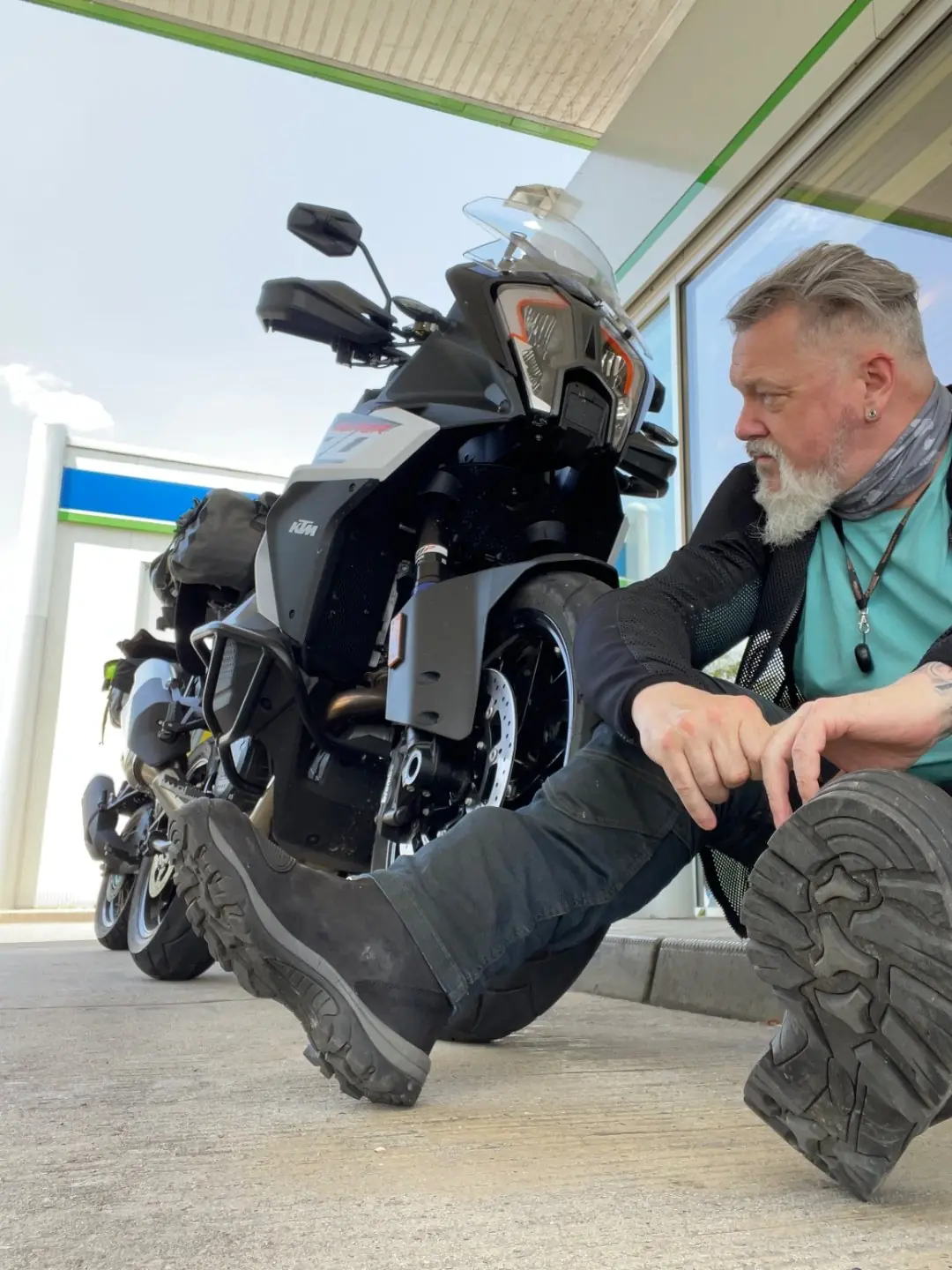Alan Jones crouched roadside beside his KTM adventure bike