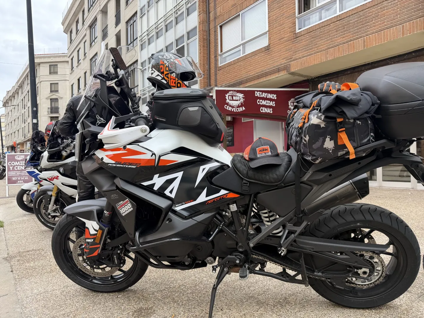 Loaded adventure bikes with luggage and tank bags parked outside a Spanish cafe in the morning