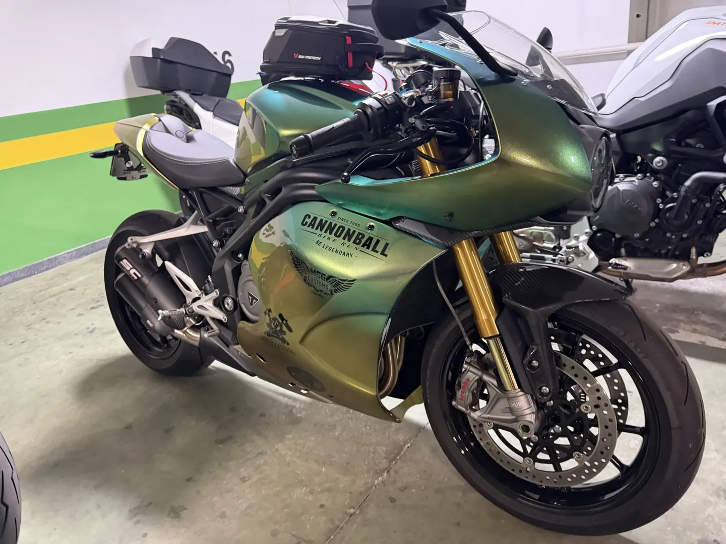 Triumph sportsbike in Cannonball Bike Run livery parked in a hotel garage before the start