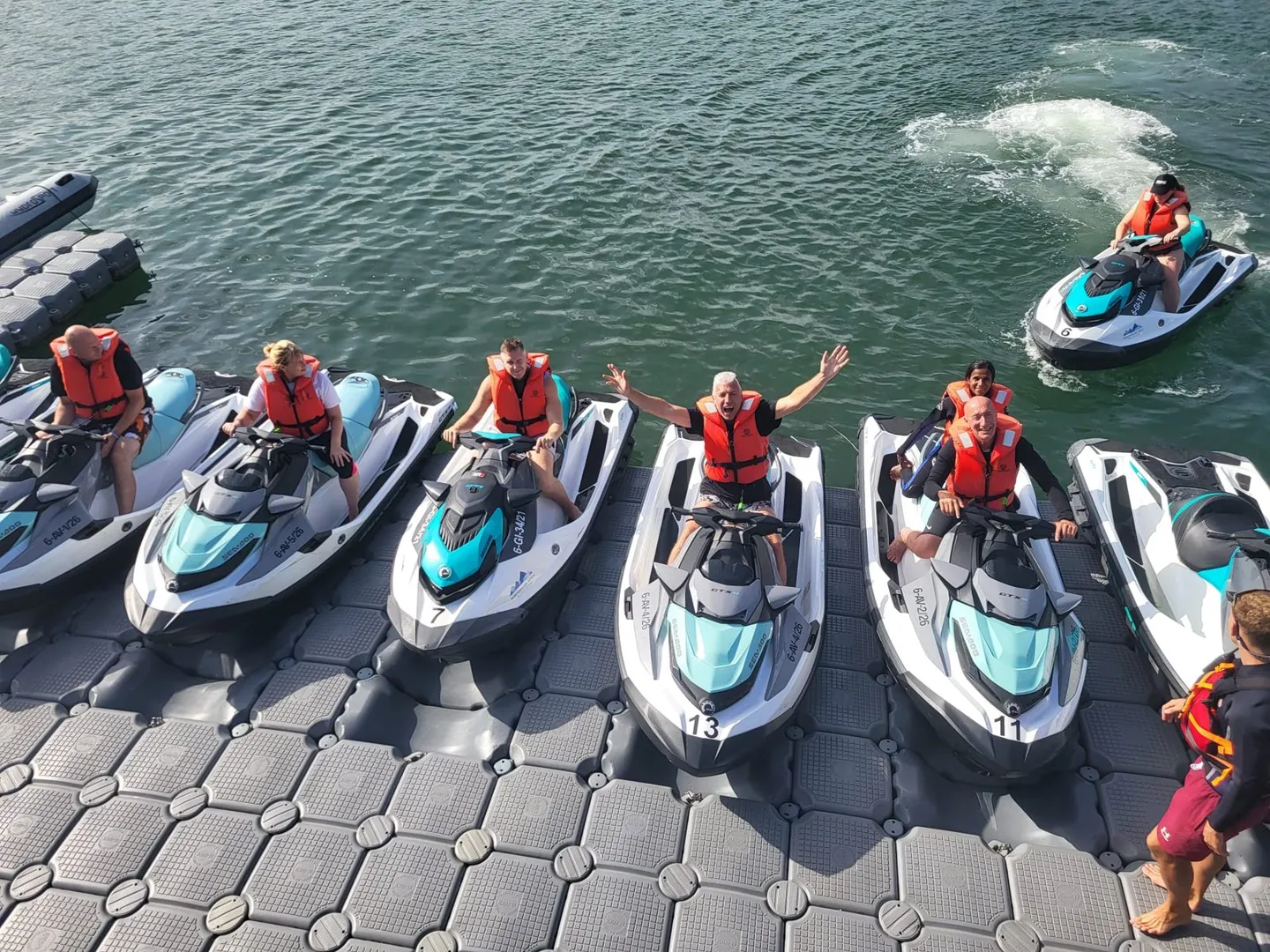 Cannonball riders in life jackets lined up on jet skis at a floating pontoon on day one of the route