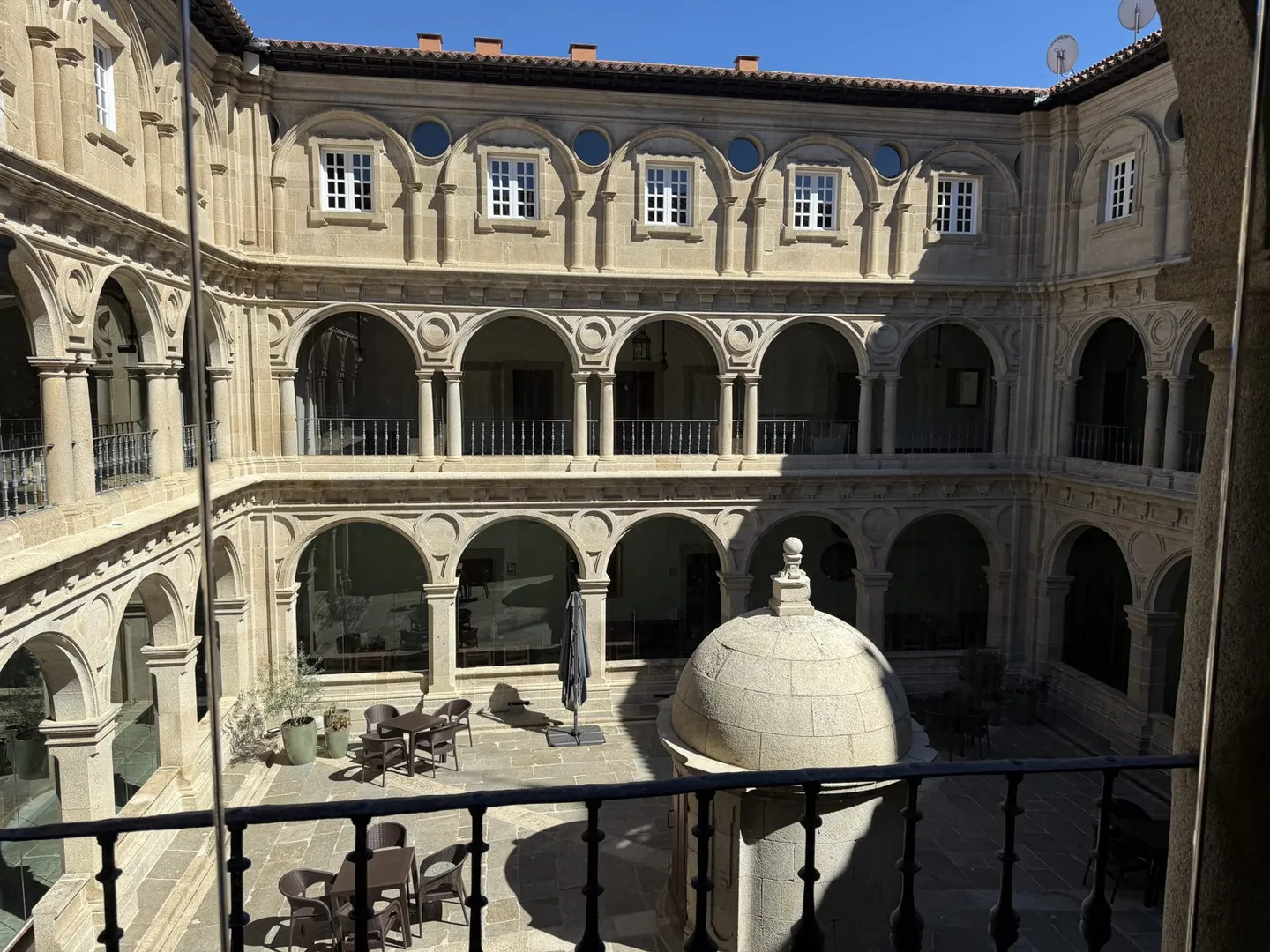 Arched stone cloister courtyard of a converted monastery hotel seen from a balcony